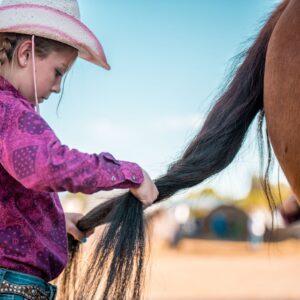 girl braiding horse's tail